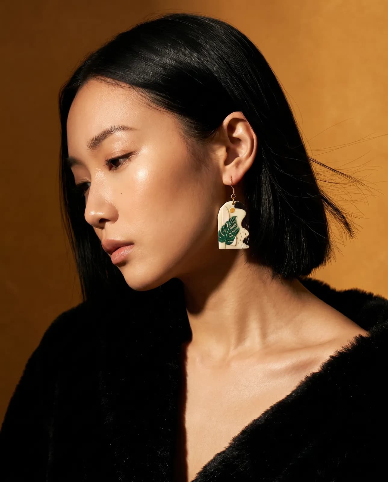 Model wearing Lily Boutique monstera-leaf earrings in warm light