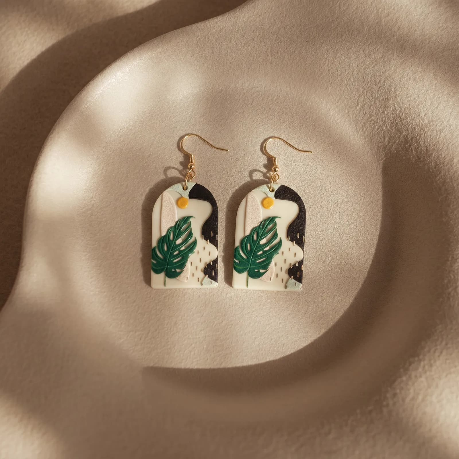 Monstera-leaf earrings on a soft neutral backdrop